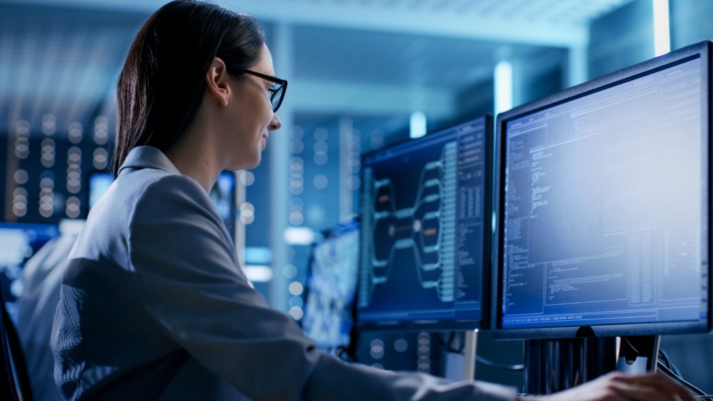 Female computer engineer coding on a desktop screen.