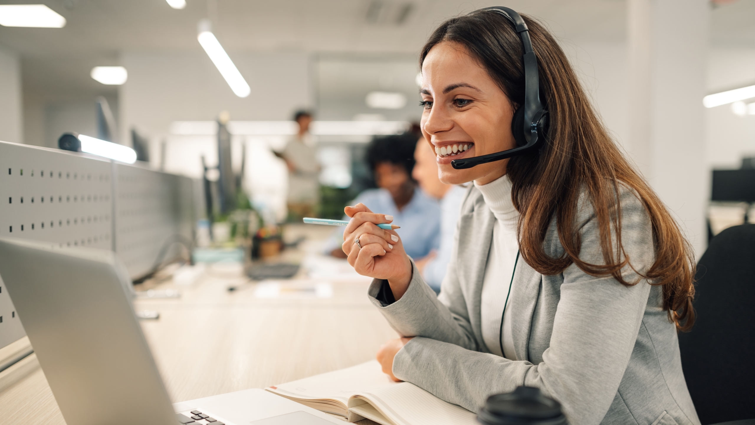 Smiling female office worker on a call using a unified communications solution, wearing a headset.